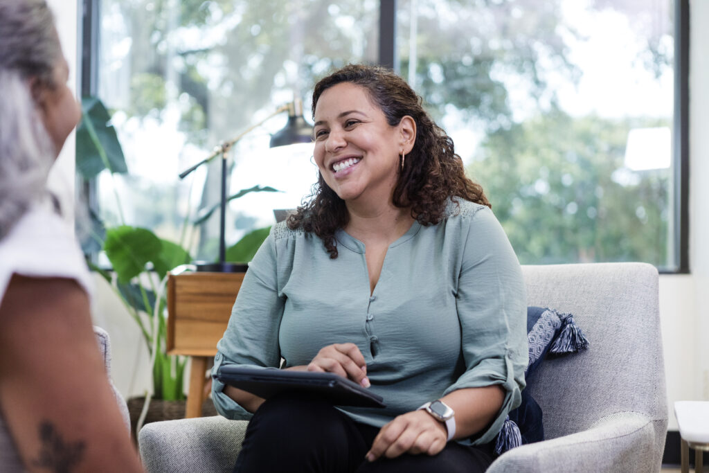 While meeting with her unrecognizable patient, the mid adult female therapist smiles.